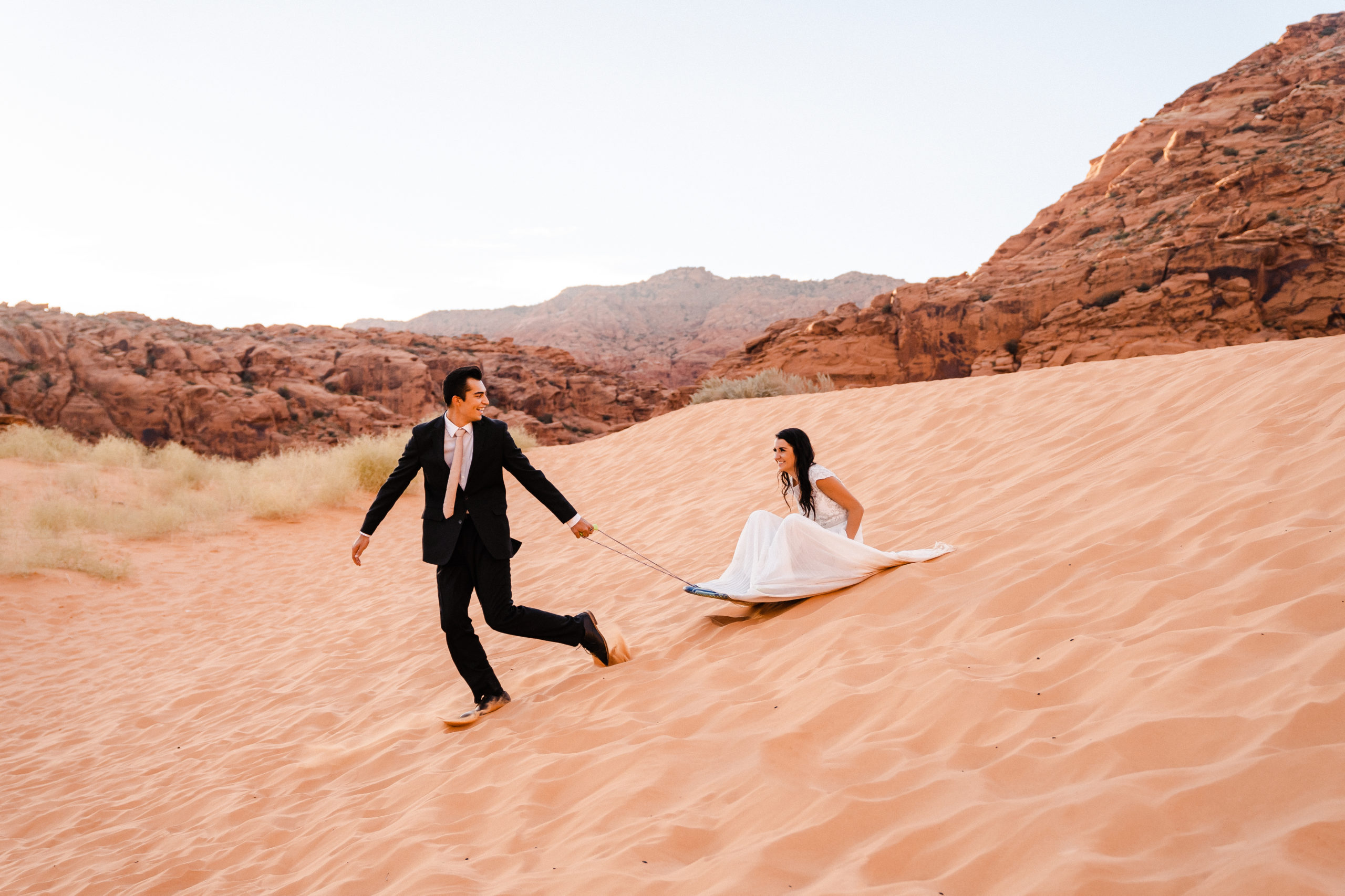 Bride and groom sand surfing in Southern Utah