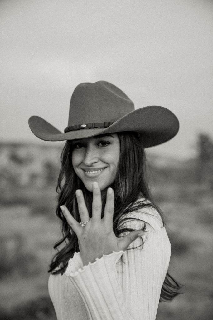 engagement picture of girl in cowboy hat showing ring