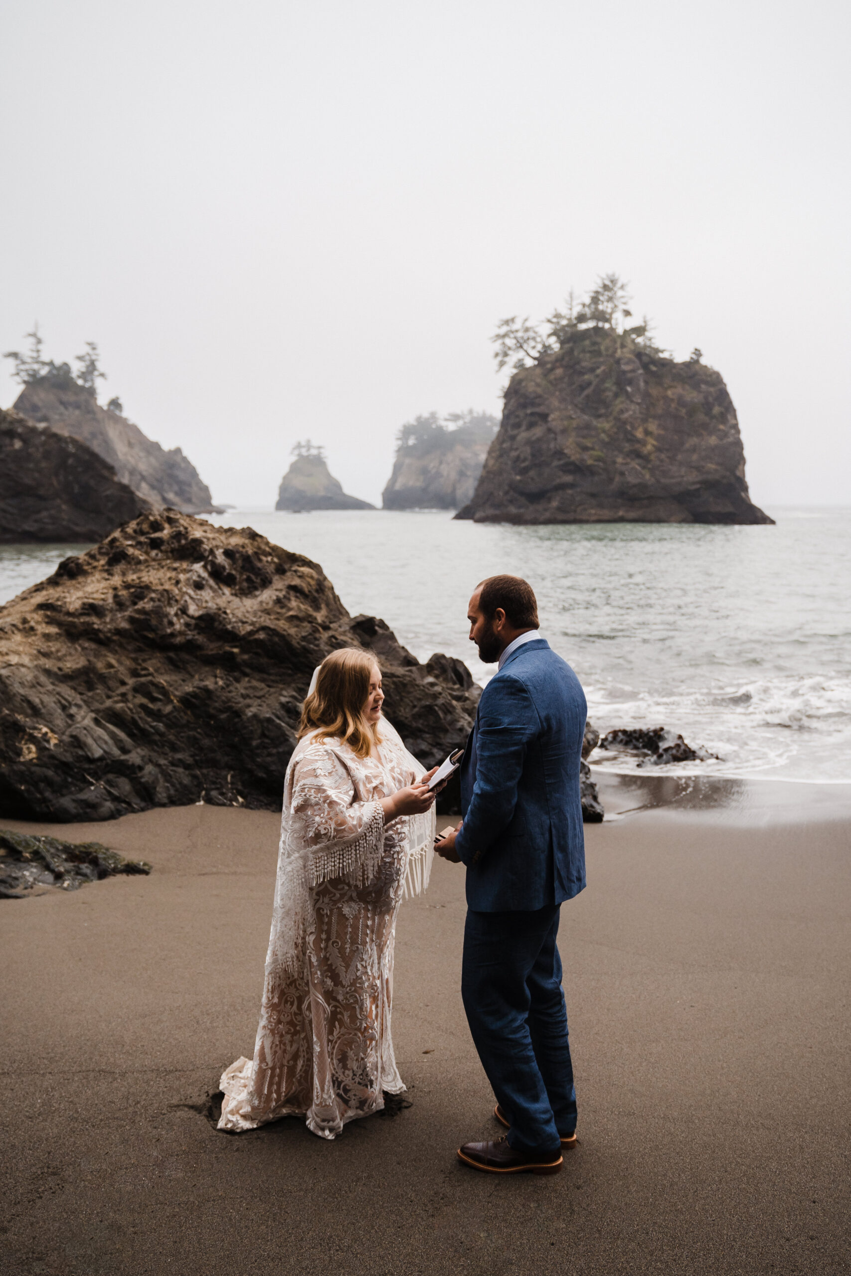 eloping couple during ceremony on oregon black sand beach